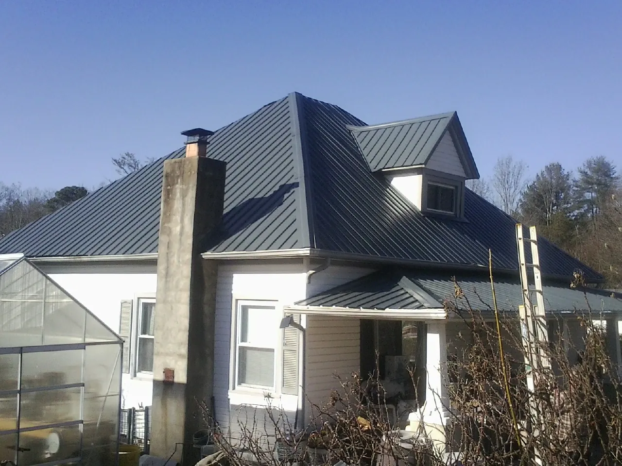 Dark blue standing seam metal roof on a white farmhouse with dormer — Slate & Tile Roof Repair by Roofing Brothers in South Whitley