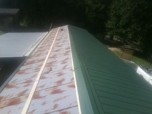 Old rusted panels beside newly installed green metal roofing — Wind Damage Roof Repair by Roofing Brothers in South Whitley