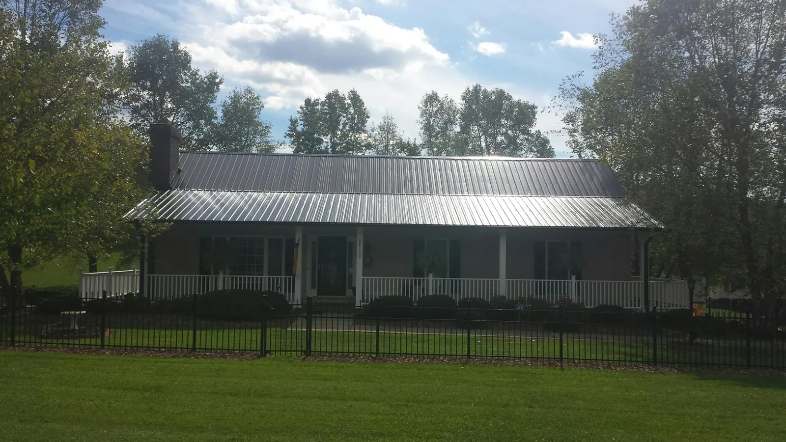 Gray metal roof on a brick ranch with a full width front porch — Gutter Guard Installation work by our crew in South Whitley