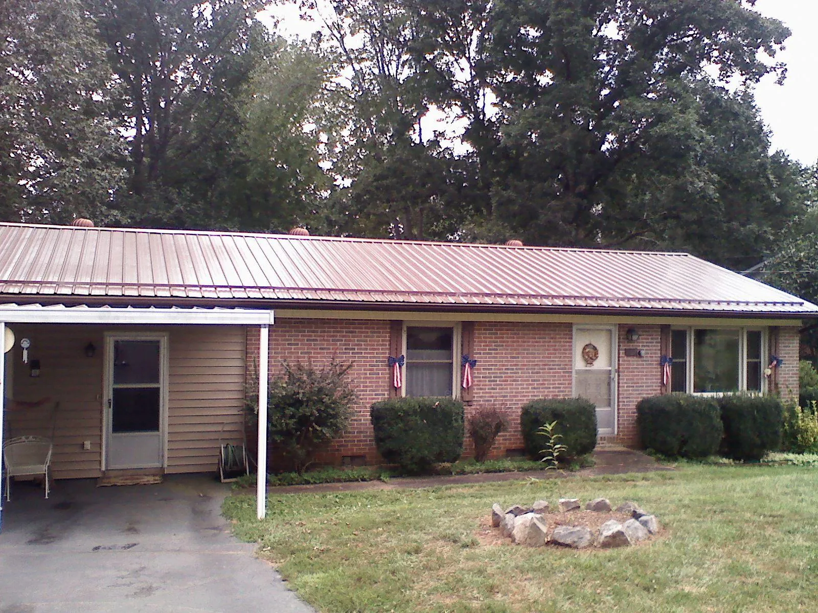 Bronze metal roof and carport on a brick ranch home — Roof Repair work by our crew in South Whitley