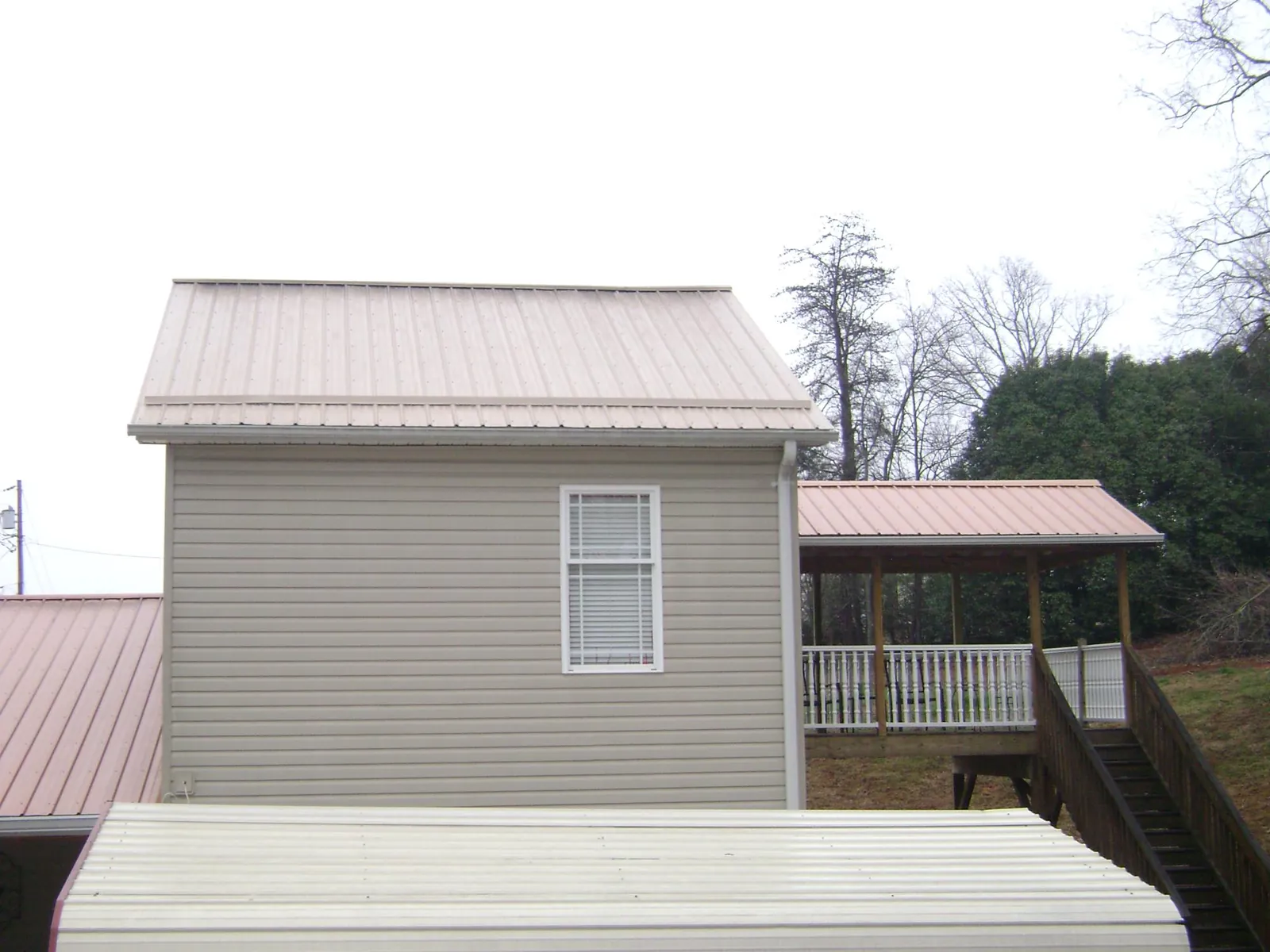 Tan metal roofs on a two story addition and attached porch, from a Roof Replacement job in South Whitley