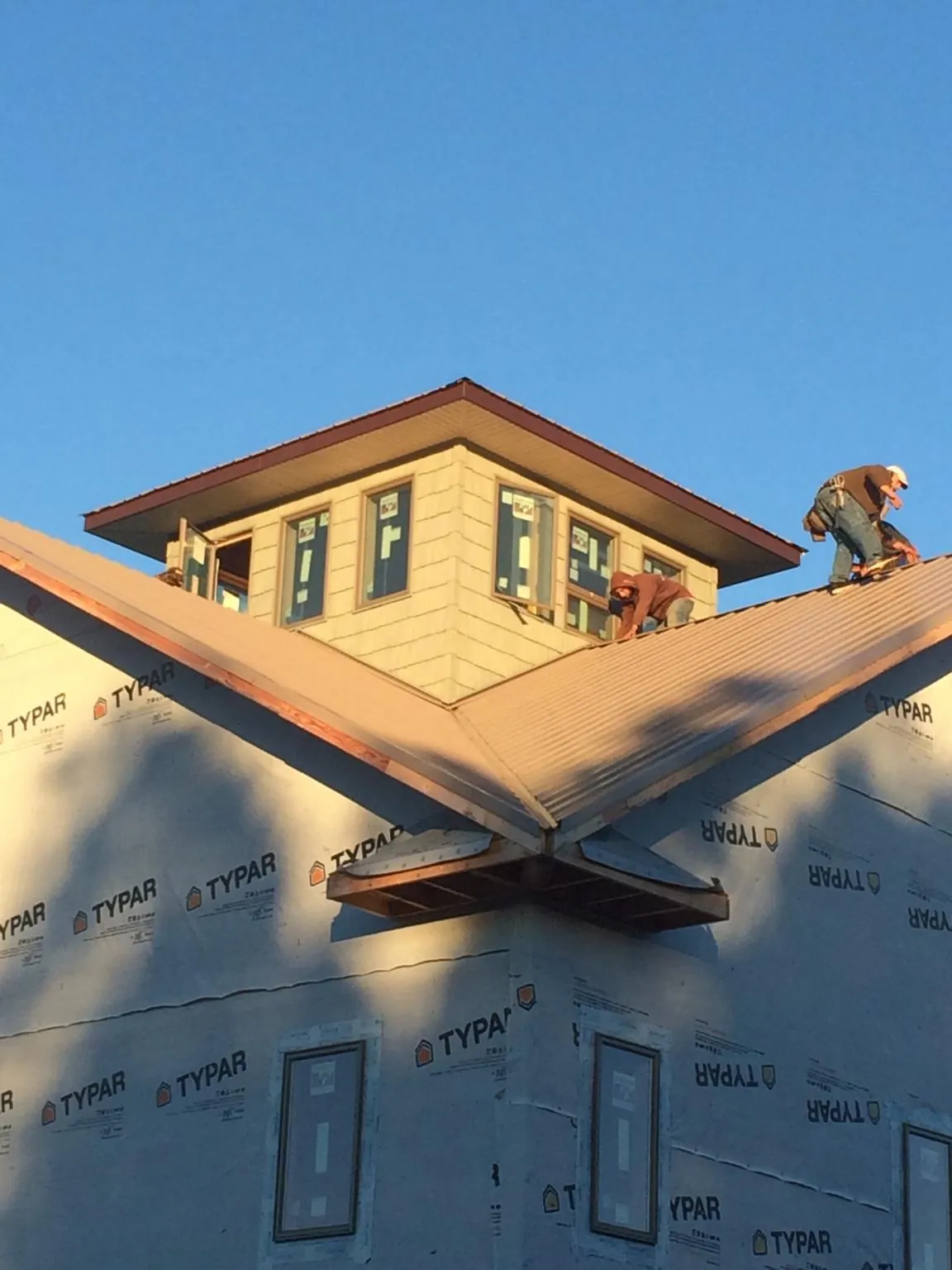 Roofers working around a rooftop cupola on a new metal roof at sunset — Roof Waterproofing in South Whitley by Roofing Brothers